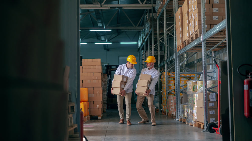 Symbolbild Firmenumzug, Männer tragen Kisten in einem Lager